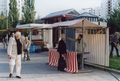 Marktstand mit rot-weiß gestreiftem Pavillon, an dem Petra Spielhagen mit Menschen Bilder gegen Geschichten tauscht.