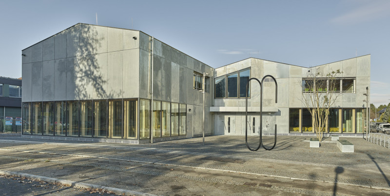 Großformatige Metallskulptur in Form einer Büroklammern vor der Fassade eines Gebäudes.