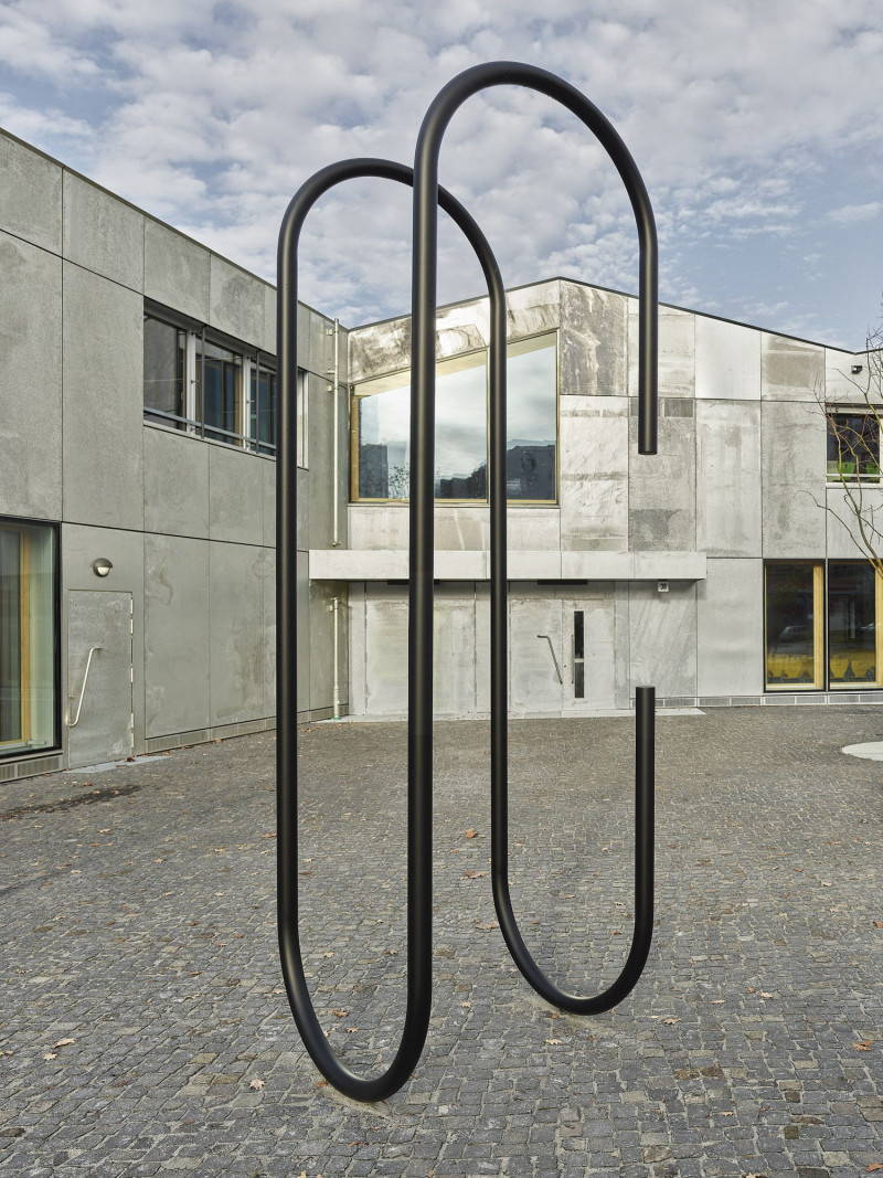 Großformatige Metallskulptur in Form einer Büroklammern vor der Fassade eines Gebäudes.