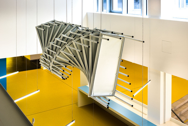 Installation aus mehreren Tischen an der Decke eines Schulgebäudes angebracht.