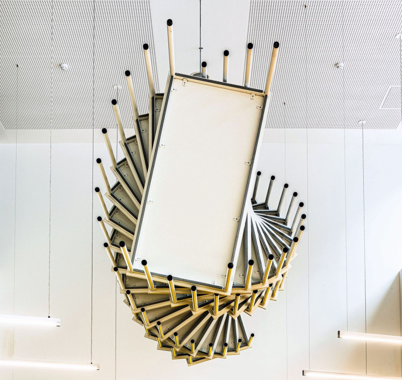 Installation aus mehreren Tischen an der Decke eines Schulgebäudes angebracht.