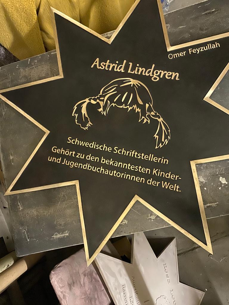 Prozess einer Gedenkplatte mit Metallporträt und Inschrift über eine Persönlichkeit.