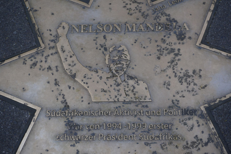 Gedenkplatte mit Metallporträt und Inschrift über eine Persönlichkeit im Boden eines Schulgebäudes eingelassen.