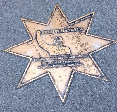 Gedenkplatte mit Metallporträt und Inschrift über eine Persönlichkeit im Boden eines Schulgebäudes eingelassen.