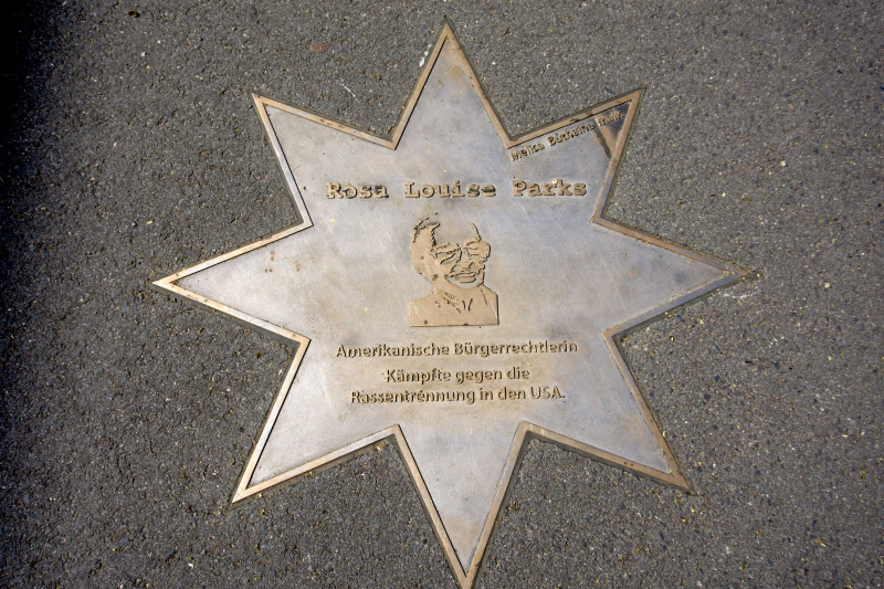 Gedenkplatte mit Metallporträt und Inschrift über eine Persönlichkeit im Boden eines Schulgebäudes eingelassen.