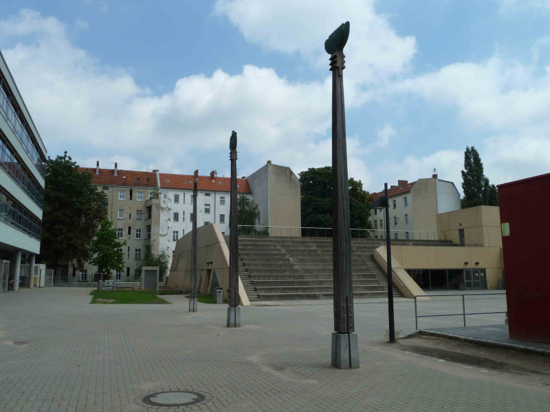 Drei lange Skulpturen im Platz vor einer Schule