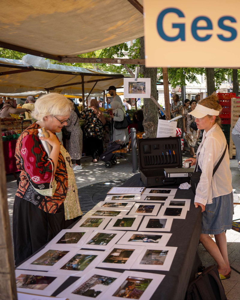 text: >
  Besucherin betrachtet ausgestellte
  Fotografien von Petra Spielhagen an
  einem Tisch auf einem Marktstand
decorative: false
source: reviewed