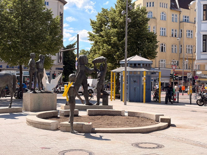 text: >
  Bronzeskulpturengruppe auf einem
  öffentlichen Platz zeigt mehrere
  menschliche Figuren in verschiedenen
  Positionen, eine davon mit gelben Armen
  auf dem Rücken
decorative: false
source: reviewed