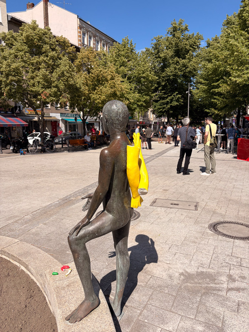 text: >
  Bronzeskulptur eines Jungen mit zwei
  gelben Armen auf dem Rücken
decorative: false
source: reviewed