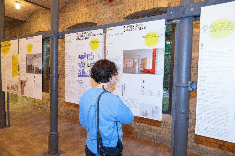 Besucherin liest eine Kunst am Bau Plakat in einer Ausstellung