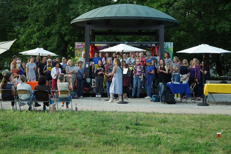 text: >
  Große Gruppe von Menschen bei einer
  Offenen Chorprobe im Park unter einem
  Pavillon und weißen Sonnenschirmen
decorative: false
source: reviewed
